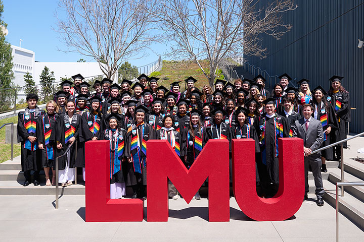 A large group of graduates standing behind large LMU letters